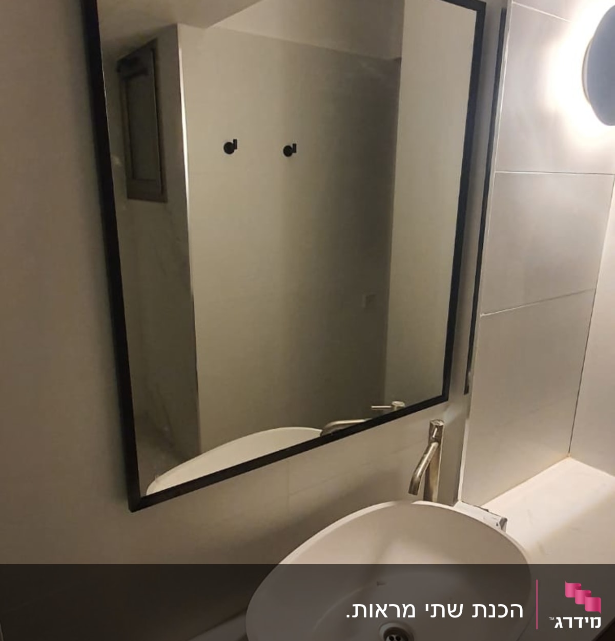 מראה מלבנית עם מסגרת שחורה בחדר אמבטיה